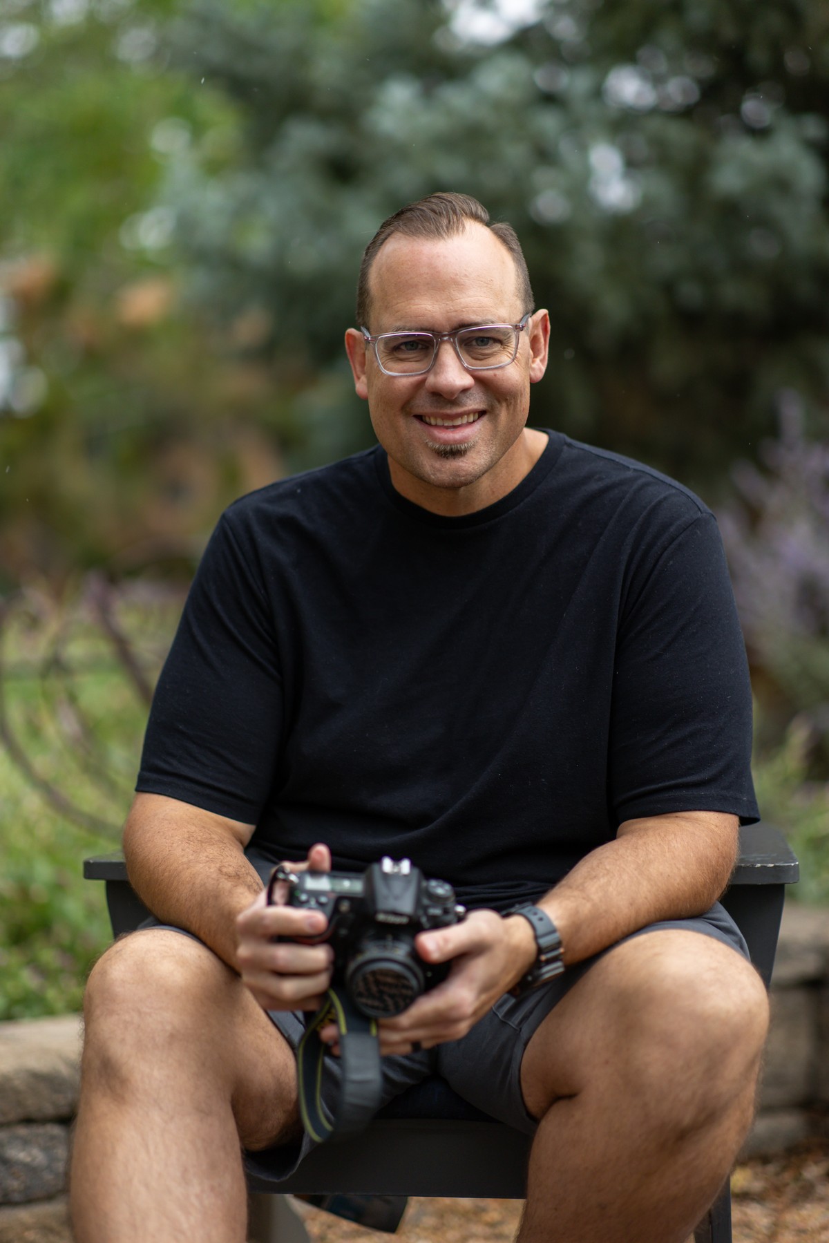 Foster Cryer seated outdoors holding his camera